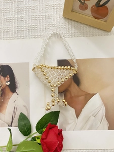 Artistic handmade crystal beaded handbag with gold accents on fashion magazine background