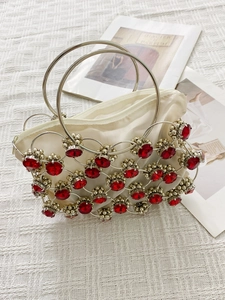 Close-up of white satin handbag with silver chain mesh and red gemstone embellishments