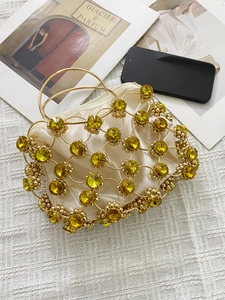 Detail of luxury gold metal mesh handbag featuring large yellow gems and a satin pouch