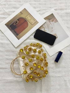 Flat lay of luxury gold mesh handbag with yellow crystals and elegant metal handles