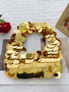 Close-up of golden oversized sequins on the fabric of this stylish handmade handbag