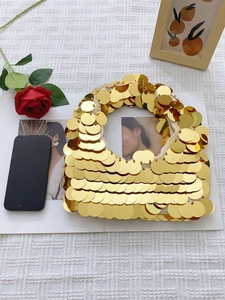 Detailed top view of gold sequin hobo bag with fish scale pattern on white textured cloth
