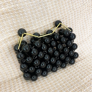 Close-up of handmade beaded mini bag with shiny black beads and gold metal handle