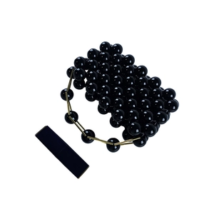 Detailed view of handmade black beaded mini bag with gold-tone handle and lipstick accessory