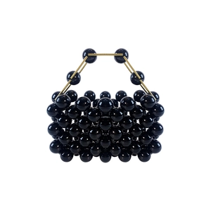 Detail of handmade black beaded mini handbag with golden metal top handle structure