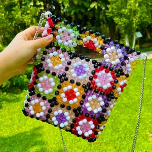 Detailed close-up of handmade colorful floral beaded crossbody bag with silver chain