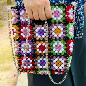 Close-up of colorful handmade beaded crossbody bag with floral pattern and silver chain
