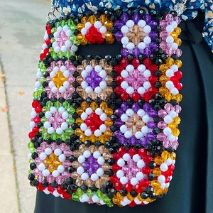 Handmade colorful beaded crossbody bag with flower patterns worn in outdoor setting