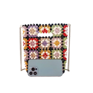 Detail view of handmade beaded crossbody bag with floral pattern and silver chain strap