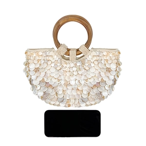 Détail du sac à main texture coquillage avec anses rondes et smartphone pour l'échelle