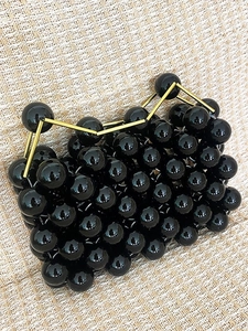 Handmade black beaded handbag with gold metal handle in minimalist fashion style