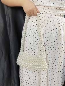 Detail of white faux pearl beaded handbag with handmade woven texture and top handle