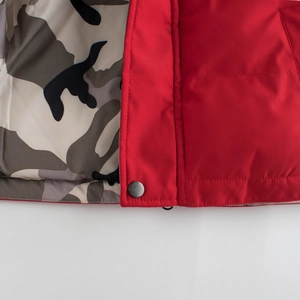 Detail of red windproof winter jacket for boys with camouflage lining and snap button