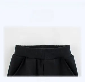 Close-up of black knitted joggers featuring a ribbed elastic waistband and side pocket detail