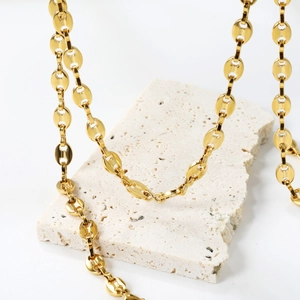 Détail du collier maille grain de café plaqué or 18 carats sur pierre travertin