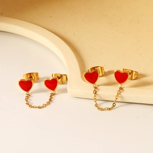 Dettaglio di orecchini a catena con cuore rosso e doppi perni in finitura oro lucido