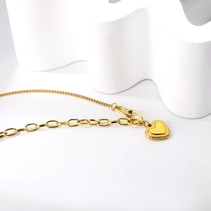 Detail of 18K gold-plated heart pendant necklace with unique mixed chain design on stone
