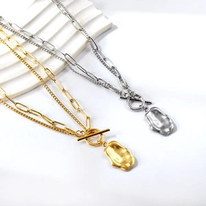 Detail of layered gold and silver OT buckle necklaces with irregular wave heart pendants