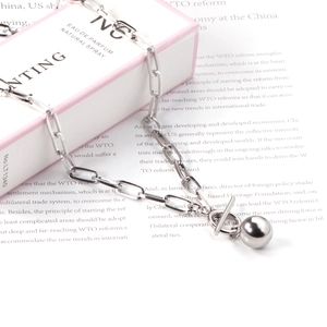 Detailed shot of silver OT buckle necklace with sphere pendant on a perfume gift box