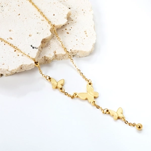 Detail of 18K gold-plated butterfly tassel necklace on white mineral stone