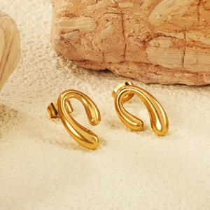 Détail de boucles d'oreilles en C dorées géométriques avec finition polie sur pierre