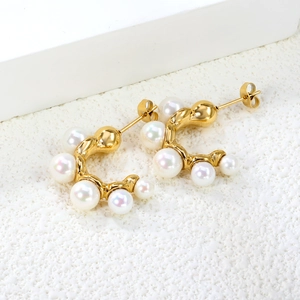 Boucles d'oreilles créoles dorées 18 carats avec perles blanches sur fond minimaliste