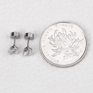 Detail view of four-prong silver stud earrings with round cubic zirconia on white leather