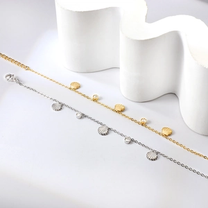 Détail de bracelets coquillages en or et argent avec zircons blancs sur fond blanc épuré