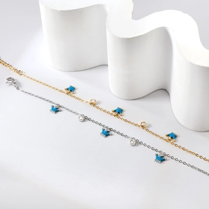 Détail de bracelets or et argent avec breloques couronne bleues et zircons