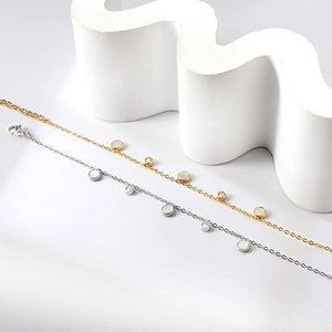 Détail de bracelets dorés et argentés avec des charmes en nacre blanche et zircon