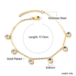 Détail d'un bracelet en acier inoxydable doré avec cinq breloques rondes en zircone