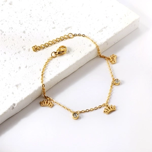Bracelet doré avec pendentifs couronnes et pierres sur support en pierre