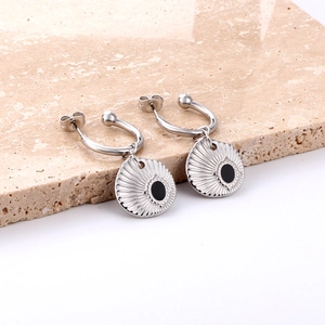 C-shaped geometric earrings with black shell design on a textured stone display