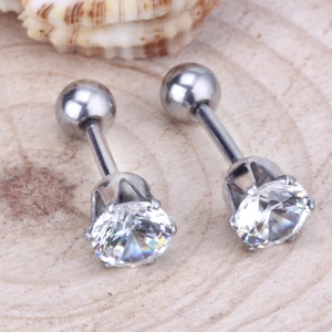 Détail de boucles d'oreilles zircone ronde avec fermoirs à vis sur surface en bois