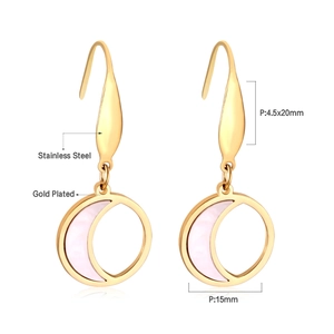 Détail de boucles d'oreilles en acier doré avec pendentif en nacre en forme de croissant