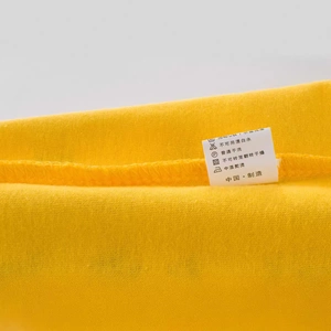 T-shirt jaune en coton pour enfants montrant l'étiquette d'entretien et les coutures