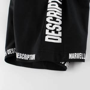 Close-up of boys' black knit shorts with white decorative letter printing on the hem