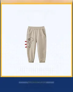 Detail of beige kids joggers featuring a cartoon dinosaur print and elastic waist