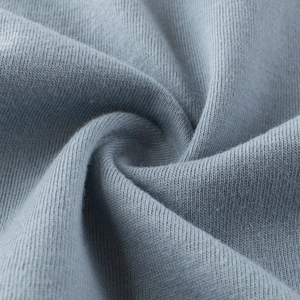Close-up of soft light blue cotton knit fabric with a smooth spiral texture for kids tops