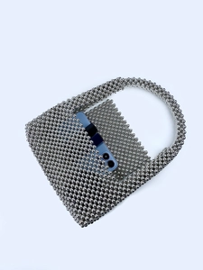 Detail of silver beaded handbag with circular handle showing size relative to a smartphone