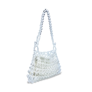 Macro detail of hand-woven clear beads and white fabric lining on a stylish shoulder bag