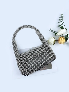 Silver beaded handbag with metallic finish and handmade woven texture on white background