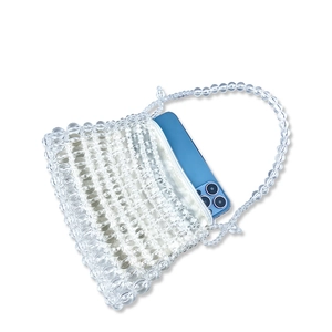 Detail view of transparent beaded handbag holding a blue smartphone for size reference