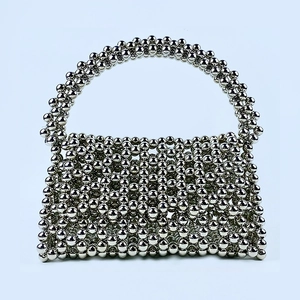 Close-up of handmade silver beaded shoulder bag with metallic hollow-out woven texture