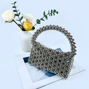 Detail of handmade silver beaded handbag with metallic mirror finish on artistic book
