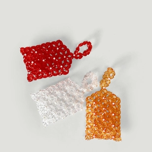 Detail view of handmade acrylic floral beaded mini bags in red, orange, and white