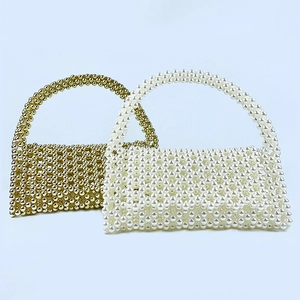 Detail of handcrafted beaded handbag featuring golden and pearl white woven textures