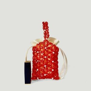 Detailed macro view of red acrylic flower beads with white pearls and satin drawstring liner