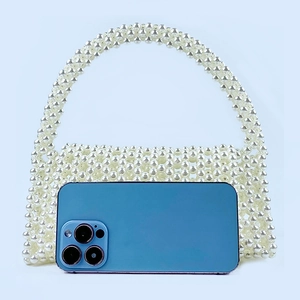 Handmade cream white beaded handbag showing size comparison with a smartphone