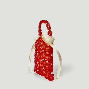 Detail of red acrylic flower beads and white faux pearls on a woven evening handbag